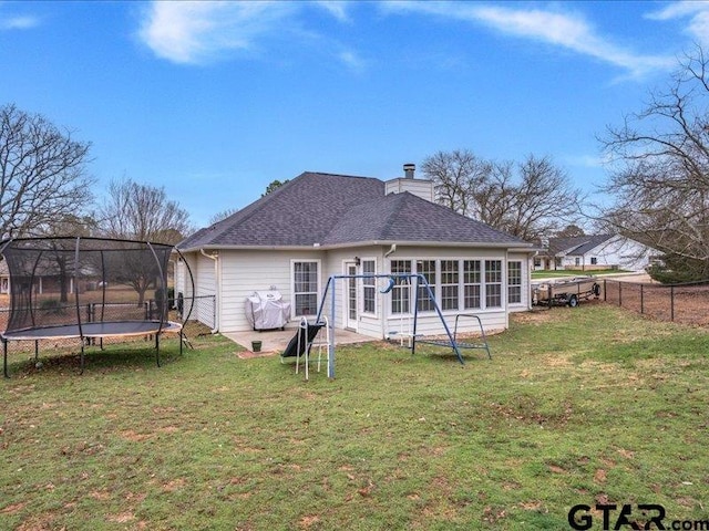 rear view of property with a patio area, a sunroom, a trampoline, and a lawn