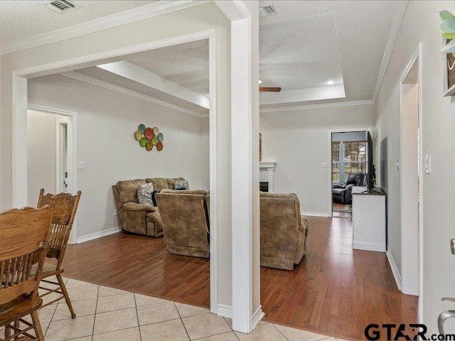 interior space featuring ornamental molding, a tray ceiling, and light tile patterned floors