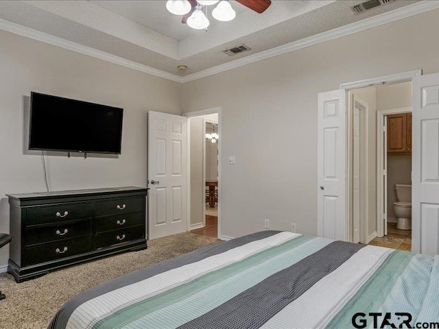 bedroom with crown molding, connected bathroom, a tray ceiling, and carpet floors