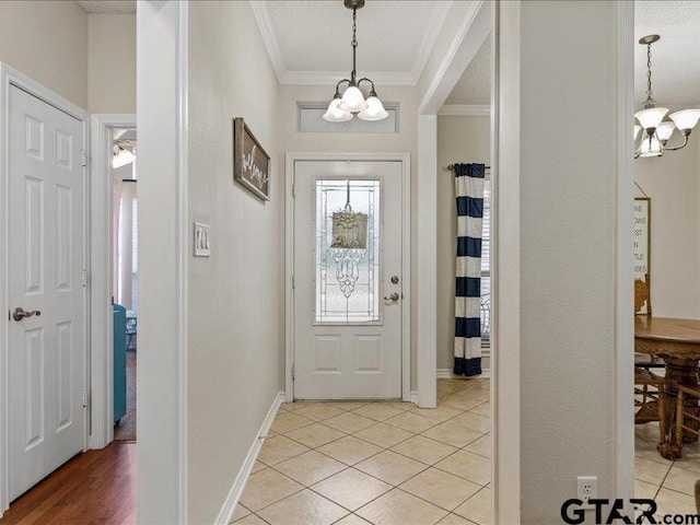 tiled foyer featuring crown molding and a notable chandelier