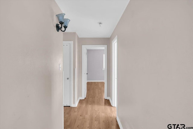 corridor with light wood-style flooring and baseboards