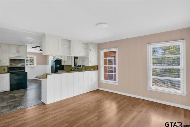 kitchen featuring open shelves, wood finished floors, range with electric stovetop, white cabinetry, and freestanding refrigerator