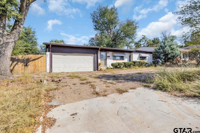 ranch-style home featuring an attached garage, fence, and driveway
