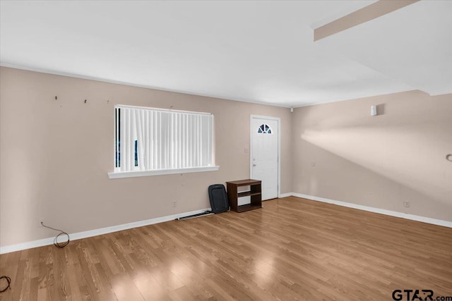 spare room with baseboards and wood finished floors