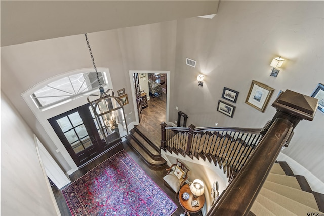 foyer entrance featuring visible vents, a towering ceiling, wood finished floors, and stairway