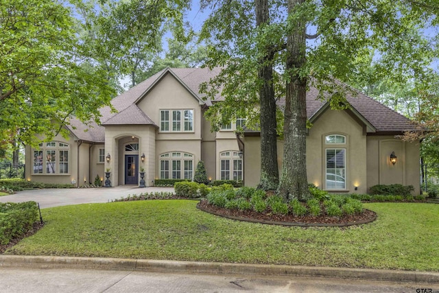 view of front facade with stucco siding, driveway, and a front lawn