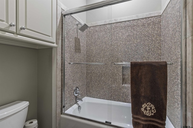 bathroom featuring combined bath / shower with glass door and toilet
