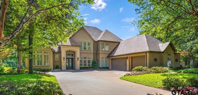 view of front of home with a garage, aphalt driveway, a front yard, stucco siding, and french doors