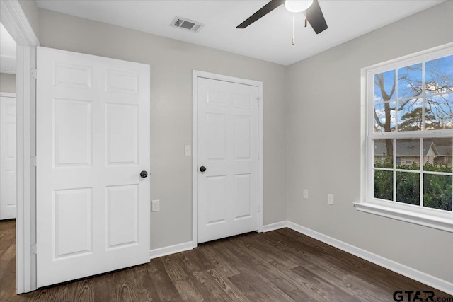 unfurnished bedroom with ceiling fan and dark wood-type flooring