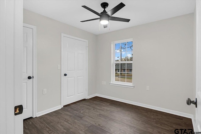 unfurnished bedroom with ceiling fan and dark wood-type flooring