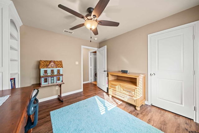 interior space featuring ceiling fan, visible vents, baseboards, and wood finished floors