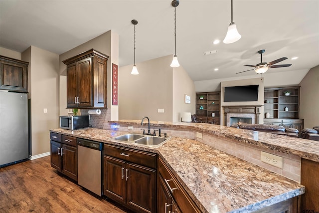 kitchen with ceiling fan, decorative backsplash, a sink, appliances with stainless steel finishes, and open floor plan