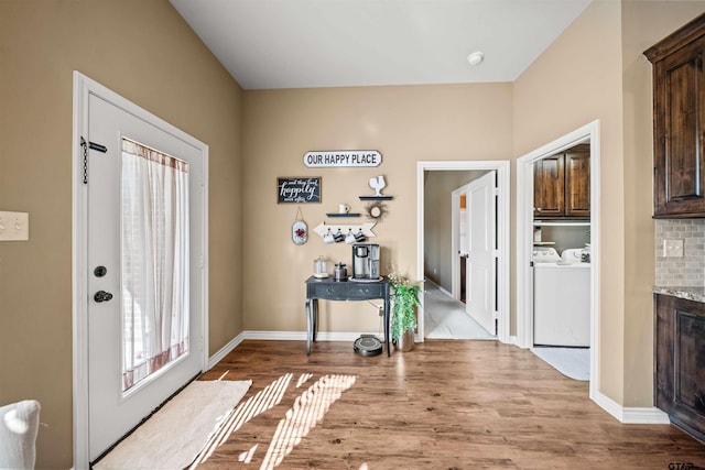 foyer entrance with independent washer and dryer, baseboards, and wood finished floors