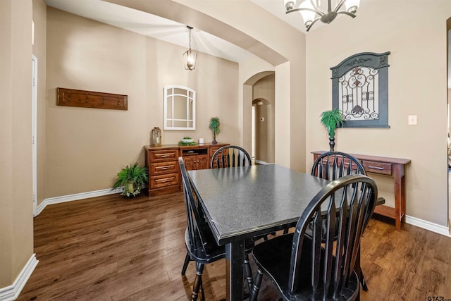 dining area featuring baseboards, dark wood-style floors, arched walkways, and a chandelier