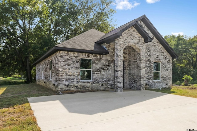 view of front of house with brick siding, roof with shingles, and a front yard