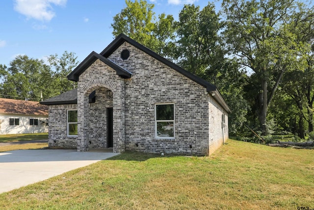 view of front of home featuring brick siding, a patio, and a front lawn