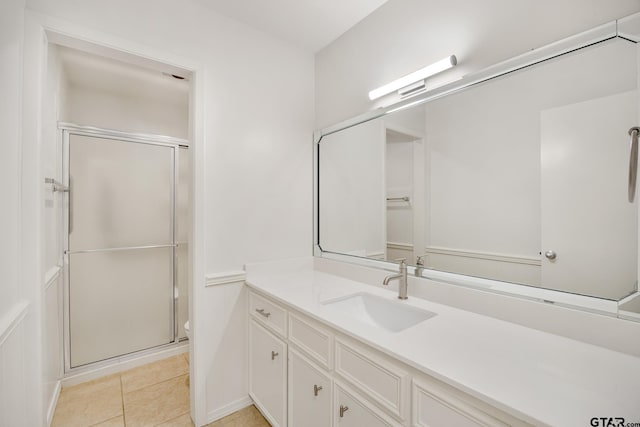 bathroom with toilet, vanity, tile patterned floors, and a shower with shower door