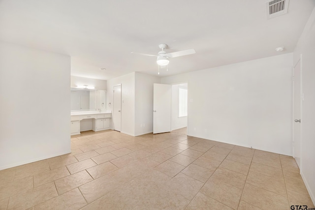 spare room with ceiling fan, built in desk, and light tile patterned floors