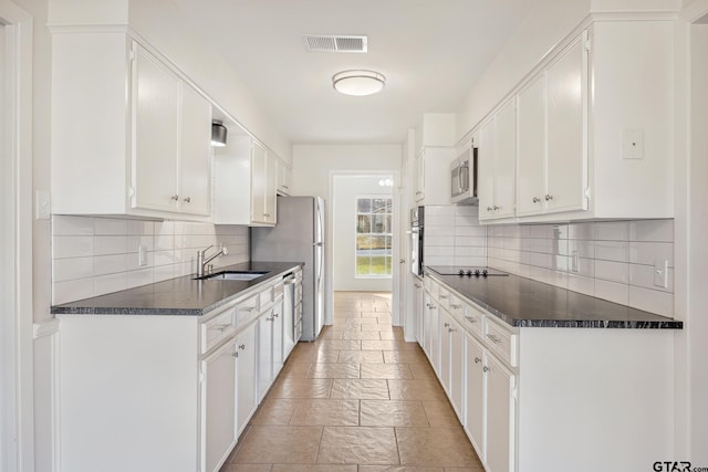 kitchen featuring tasteful backsplash, dark stone counters, stainless steel appliances, sink, and white cabinets