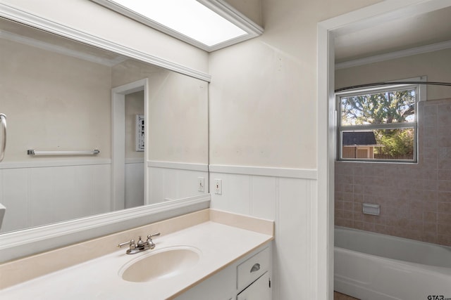 bathroom featuring crown molding, a wainscoted wall, a bathing tub, and vanity