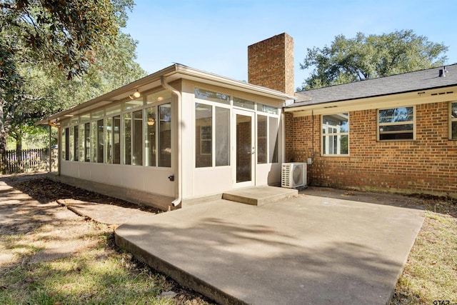 rear view of property with a patio, a chimney, a sunroom, brick siding, and ac unit