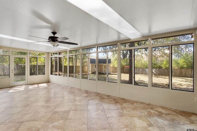 unfurnished sunroom featuring a ceiling fan and stone finish floor