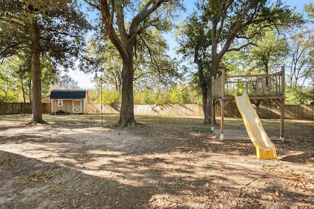 view of yard with a fenced backyard, a storage unit, an outbuilding, and a playground