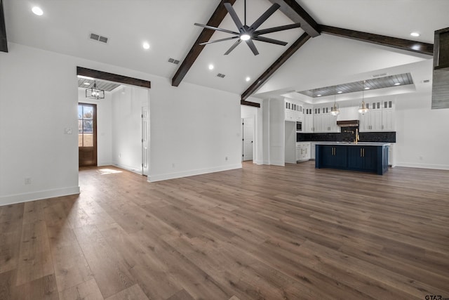 unfurnished living room featuring ceiling fan with notable chandelier, dark hardwood / wood-style flooring, high vaulted ceiling, and beamed ceiling