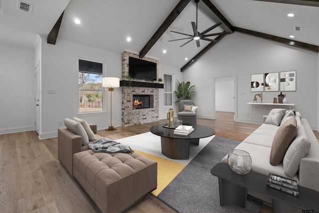 living room featuring a fireplace, light hardwood / wood-style flooring, ceiling fan, and beamed ceiling