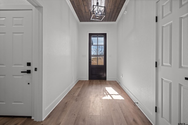 entryway featuring a chandelier, ornamental molding, wooden ceiling, and light wood-type flooring