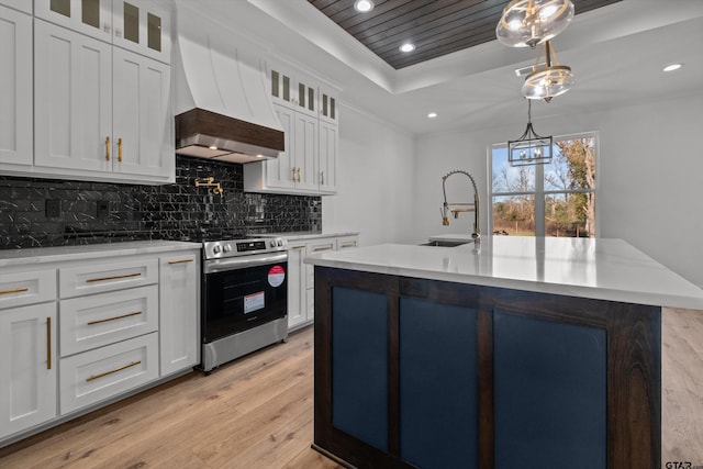 kitchen with stainless steel range with electric stovetop, a kitchen island with sink, sink, decorative light fixtures, and white cabinets