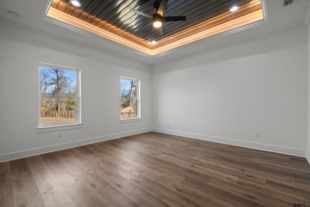 spare room with ceiling fan, wooden ceiling, a raised ceiling, dark hardwood / wood-style floors, and crown molding