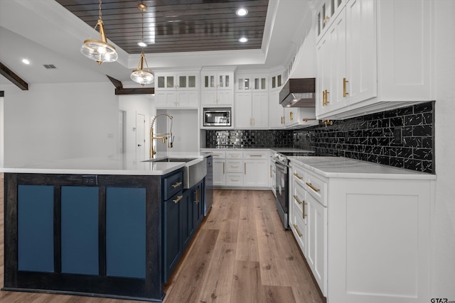 kitchen with stainless steel appliances, blue cabinetry, decorative light fixtures, white cabinets, and an island with sink