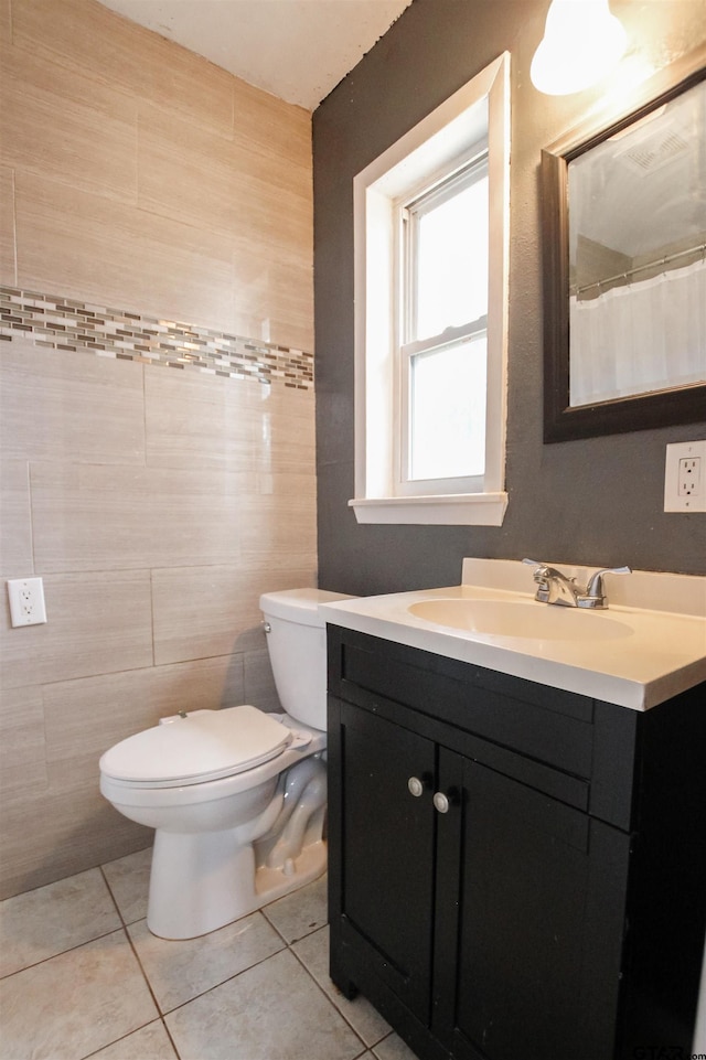 bathroom with tile patterned flooring, vanity, toilet, and tile walls