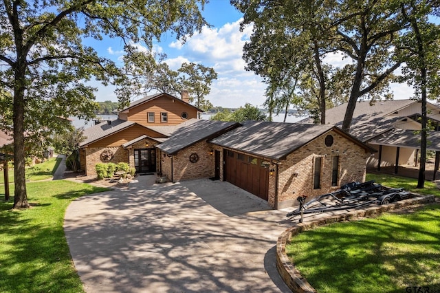 rustic home with driveway, brick siding, a front yard, and a garage