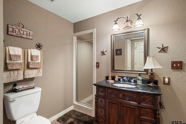 full bath with a shower stall, toilet, vanity, and a textured wall