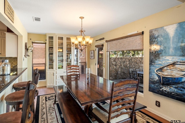 dining area with wood finished floors, a chandelier, and visible vents