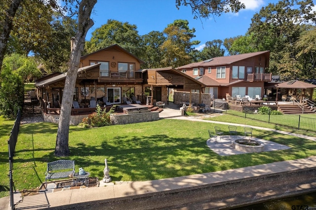 rear view of house with fence, a fire pit, a yard, and a patio