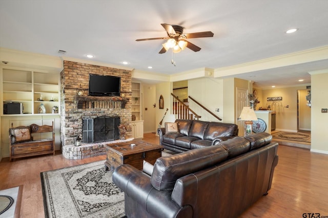 living room with a fireplace, stairway, a ceiling fan, and wood finished floors