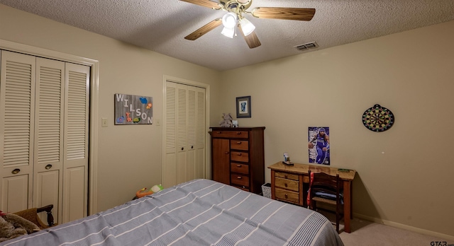 6001 Huntington Dr, Tyler, TX 75703 - bedroom featuring carpet floors, a textured ceiling, baseboards, multiple closets, and ceiling fan
