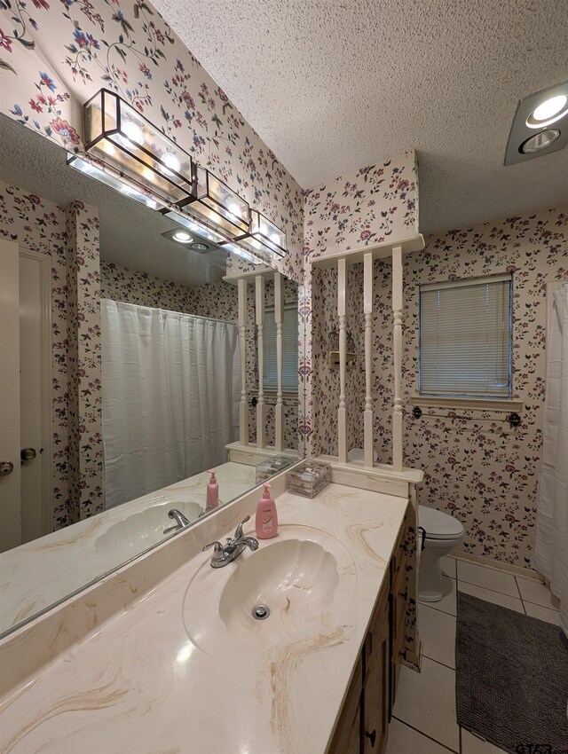 6001 Huntington Dr, Tyler, TX 75703 - full bathroom with wallpapered walls, tile patterned floors, a textured ceiling, toilet, and vanity