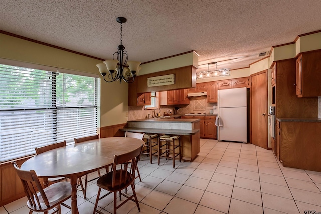 6001 Huntington Dr, Tyler, TX 75703 - dining space featuring a chandelier, a textured ceiling, a wainscoted wall, light tile patterned floors, and ornamental molding