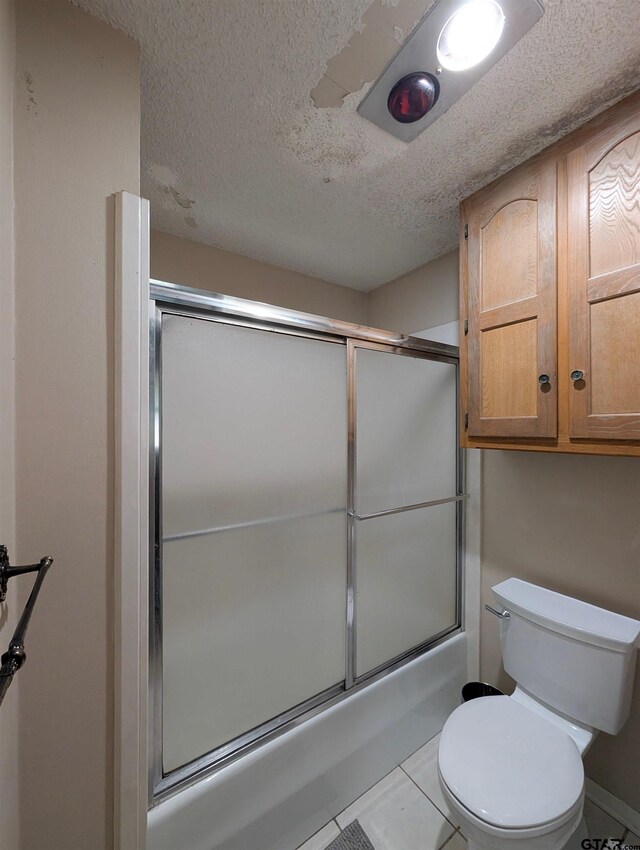 6001 Huntington Dr, Tyler, TX 75703 - bathroom featuring a textured ceiling, toilet, bath / shower combo with glass door, and tile patterned floors
