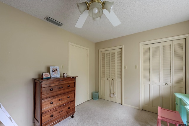 6001 Huntington Dr, Tyler, TX 75703 - bedroom featuring multiple closets, carpet flooring, a textured ceiling, and ceiling fan