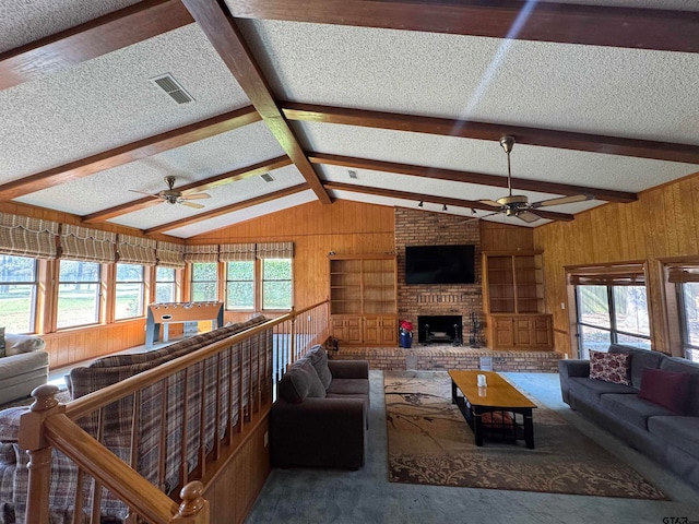 living room with vaulted ceiling with beams, wood walls, a textured ceiling, ceiling fan, and built in features