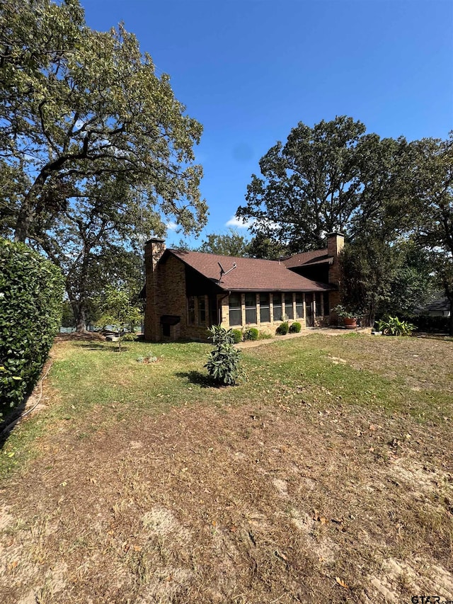 view of side of property featuring a sunroom and a lawn