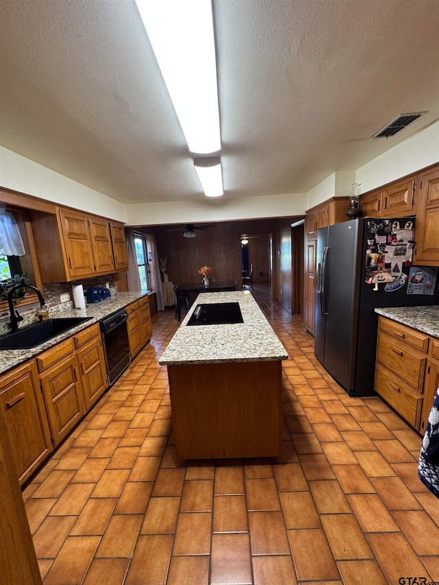 kitchen with sink, black appliances, tasteful backsplash, a textured ceiling, and a center island