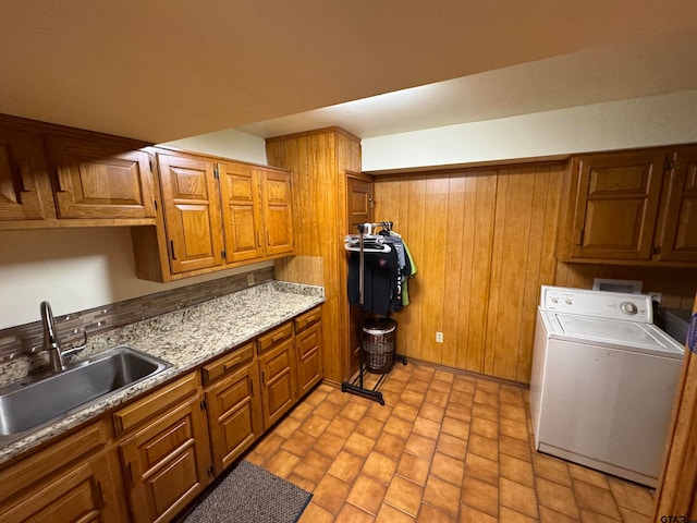 kitchen featuring wooden walls, sink, and washer / clothes dryer