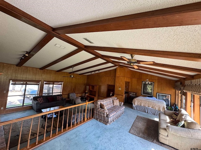 carpeted bedroom with wood walls, a textured ceiling, and vaulted ceiling with beams