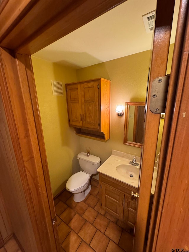 bathroom with toilet, vanity, and tile patterned flooring